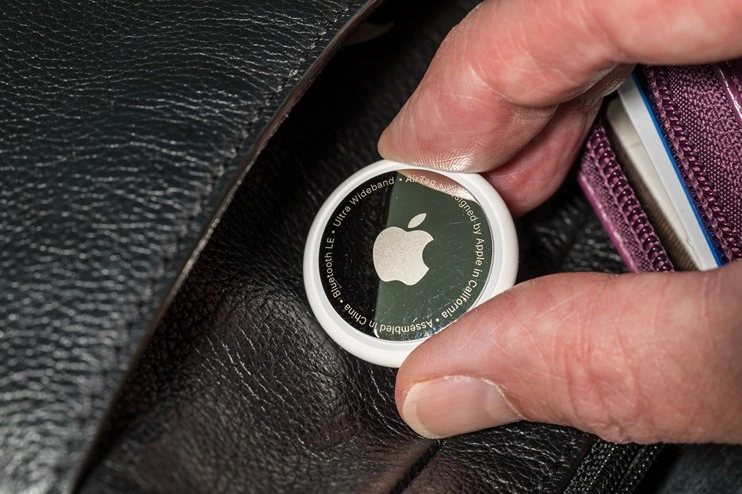 A person placing an Apple Air Tag in someone's wallet without their knowledge.